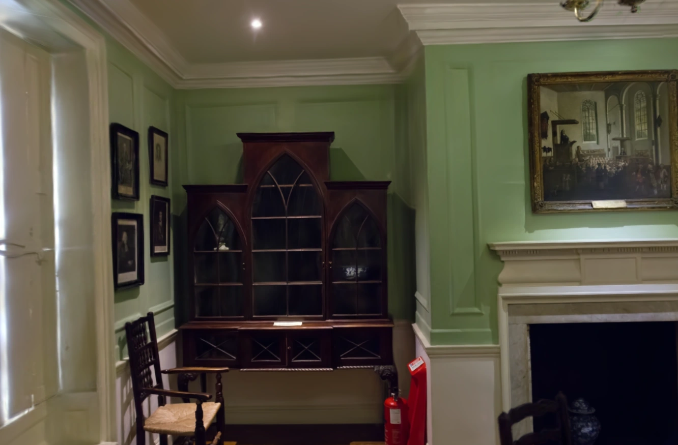 MakeWorlds render: The wooden cabinet, white fireplace, and green walls in Dr Johnson
